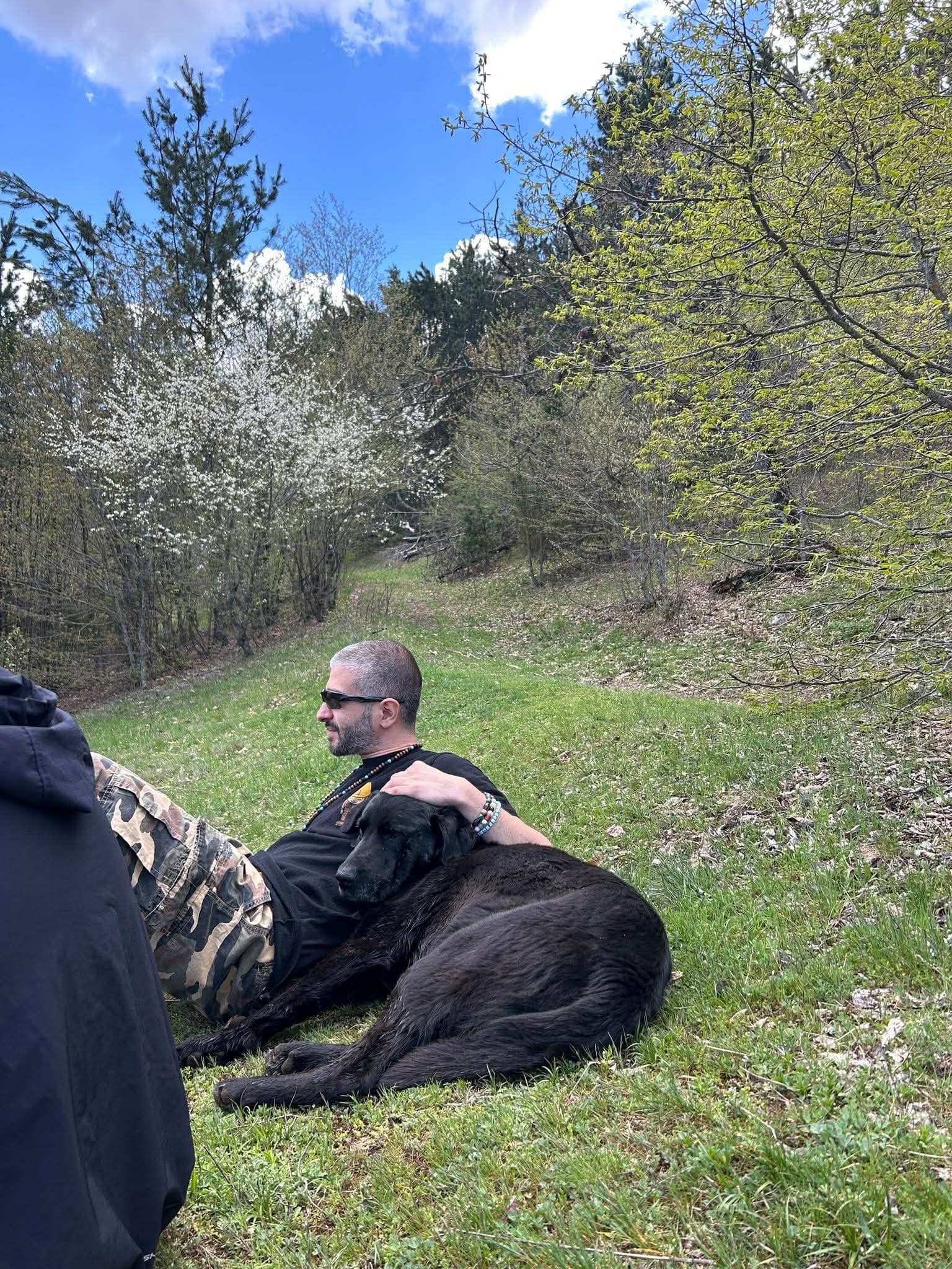 Person sitting on a grassy hill with a dog