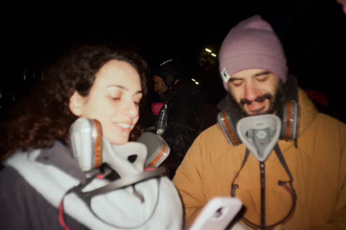 Two people wearing respirators around their necks at night
